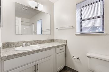 A white bathroom with a sink, mirror, and tub